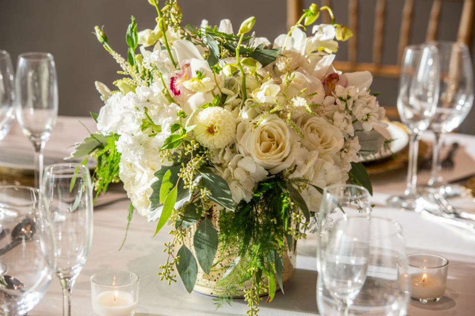 Floral arrangement ceterpiece with white flowers and accents of greenery